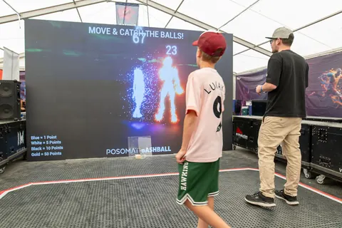 Spectators and players in front of the Bashball LED wall in the festival tent