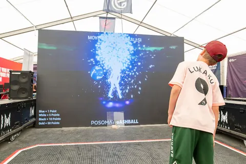 A child plays Bashball, the body appears as a glowing particle figure on the LED wall