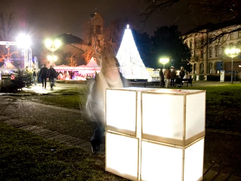 Glowing cubes on a lawn in front of an illuminated Christmas tree